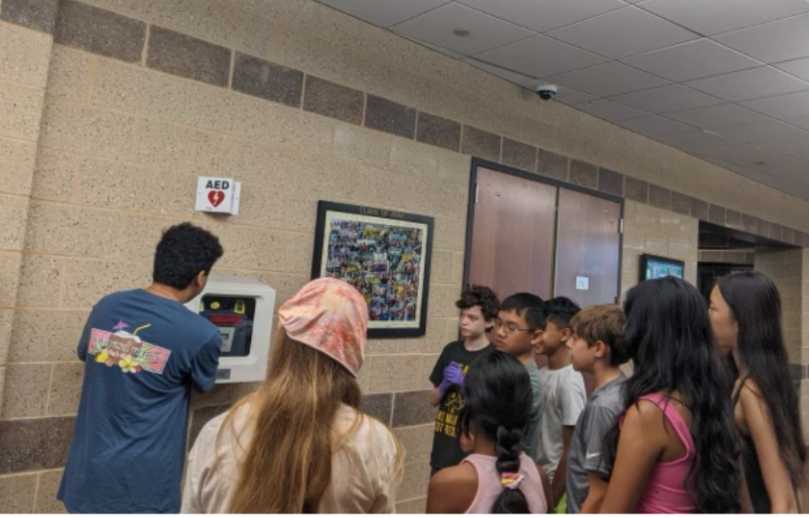 Students gather around a wall-mounted AED during a workshop