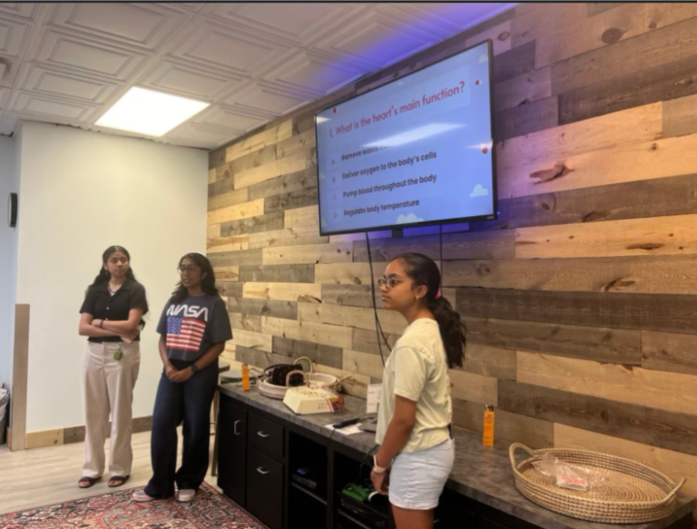 Three volunteers present a heart health slide in a small community space