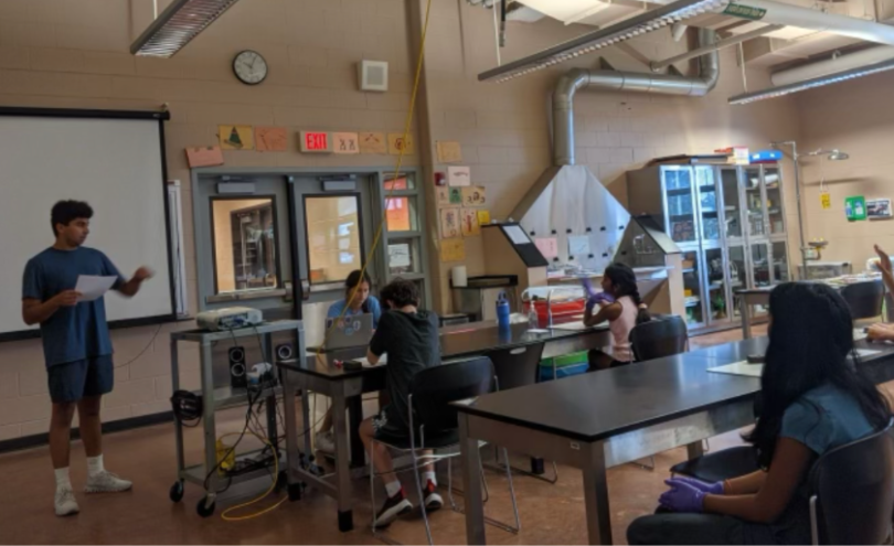 An HFH volunteer speaks to students in a school science lab