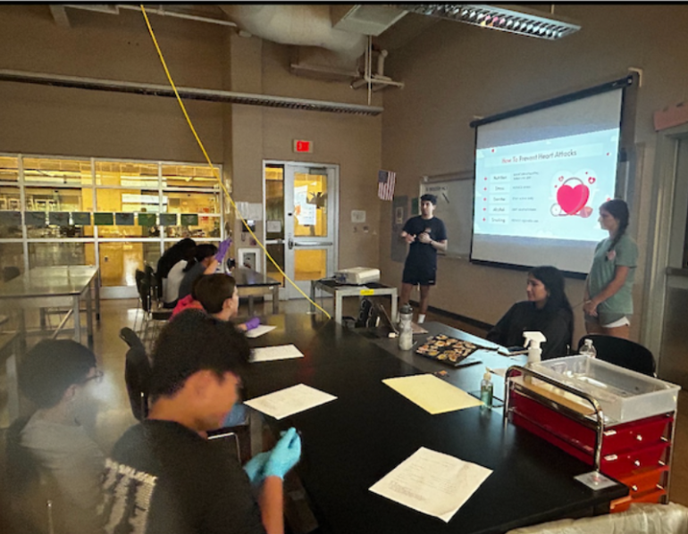 Volunteers present to middle schoolers seated at lab tables